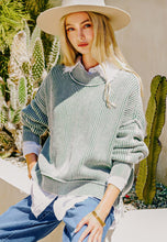 Load image into Gallery viewer, Woman wearing a light green sweater and white hat in an outdoor setting with plants.