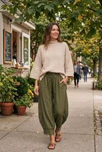 Load image into Gallery viewer, Softly Yours beige sweater styled with olive lace-trim pants on a casual sidewalk stroll